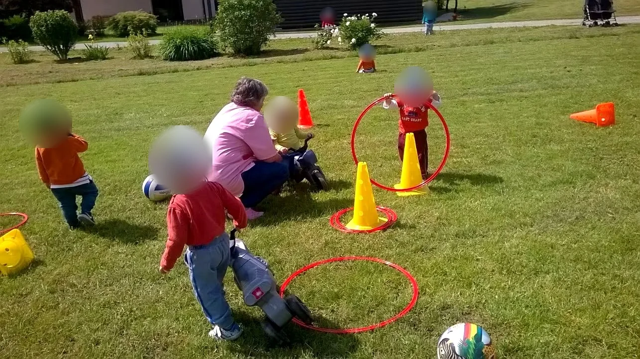 Otroci s čeladami med gibanjem in igro na travnati površini